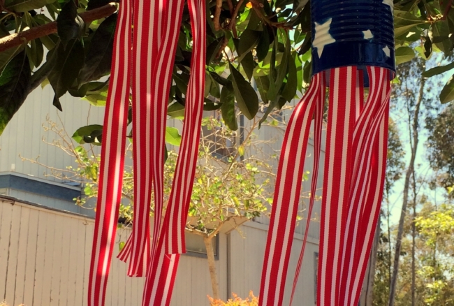 Using cans, spray paint, and ribbon, make these super cute windsocks to add a little red, white, and blue to your yard #4thofJuly #upcycled #craftproject