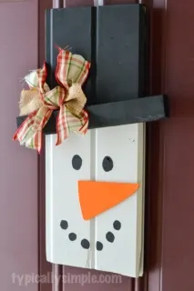 With two pieces of scrap wood, some paint, and a few other supplies from your craft stash, create this cute rustic snowman to hang on your front door!